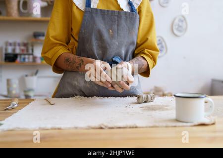 Female potter artist hands molding raw clay. Woman ceramist in apron prepare for shaping pottery Stock Photo