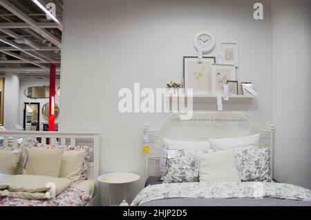 Moscow, Russia, September 2019: IKEA store bedroom interior: white color bed, linen, photo frames and wall clock. Furniture store. Stock Photo