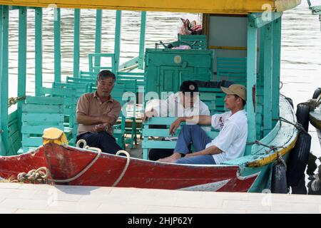 Vietnamese boat men wait for visitors on colourful, painted tourist boats moored on the Thu Bon River in Hoi An, Quang Nam province, central Vietnam Stock Photo