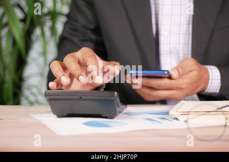 accountant using calculator and smart phone on office desk. Stock Photo