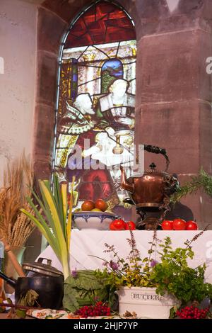 Harvest festival display in St Michael and All Angels Church, Helensburgh, Scotland showing stain glass window and various fruits and vegetables Stock Photo