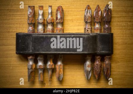 Close up shot of some used rusty screwdriver heads and bits on a wooden background. Stock Photo