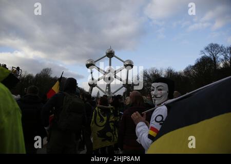Brussels, Brussels Capital Region, Belgium. 30th Jan, 2022. A protester wearing an Anonymous mask holds the Belgian flag in front of the Atomium during a demonstration asking for the resignation of Belgian government following measures imposed by Belgian authorities to contain the spread of Covid-19 in Brussels, Belgium, January 30, 2021. (Credit Image: © Valeria Mongelli/ZUMA Press Wire) Stock Photo
