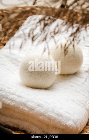 Natural wool dryer balls for more soft clothes while tumble drying in washing machine concept. Earthly tones, reed decoration. Stock Photo