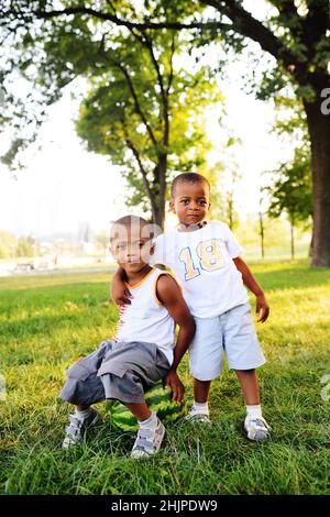 two happy black African American baby boy sitting on a big watermelon smiling on a Park Stock Photo