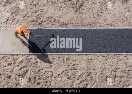 Laying worker new asphalt paving road construction site work pathway. Sidewalk construction asphalt work tarmac road worker. New road construction Stock Photo