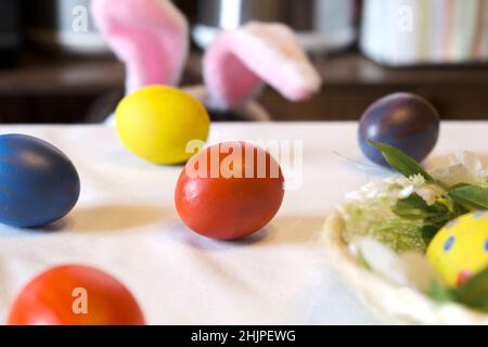 Colorful Easter eggs, paints, a nest on a white table in the dining room. Concept of preparation for Easter. Real authentic shot. Side View Stock Photo