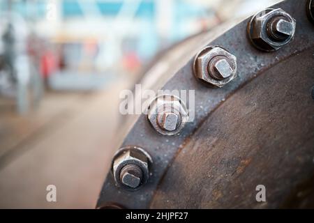 Industry flanges joint connection with screws and bolts closeup over out of focus abstract industrial background with copyspace. Bolted screw Stock Photo