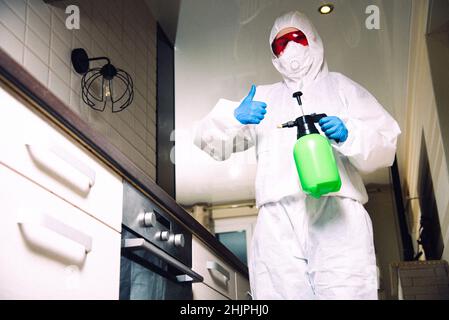 Exterminator in work clothes showing thumbs up. Fight against insects in apartments and houses. Disinsection of premises. Stock Photo