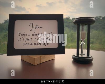 Motivational and inspirational quote on paper frame - Take a deep breath. It is just a bad day, not a bad life. With minutes glass and nature Stock Photo
