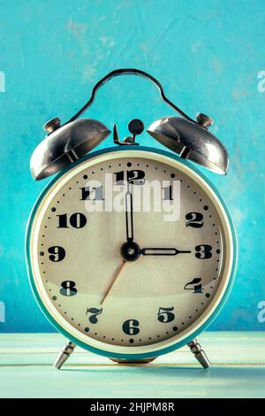 A retro alarm clock on a blue background, the concept of time shift Stock Photo