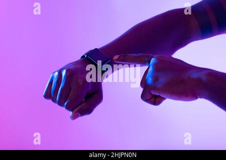 Cropped view of African American guy using smartwatch with blank screen in neon light, mockup Stock Photo