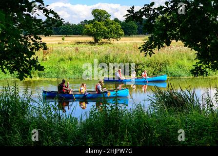 Two blue rowing boats with rowers enjoying a leisurely day out on the River Severn in the countryside near Shrewsbury Stock Photo