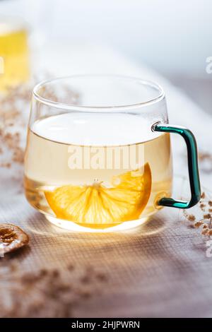 Cup of chamomile tea in transparent mug served with slice of lemon and orange. Tea break. Stock Photo