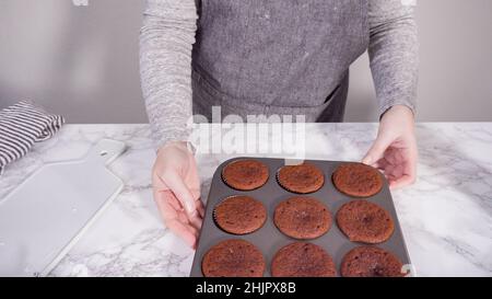 Step by step. Cooling red velvet cupcakes on a kitchen drying rack. Stock Photo