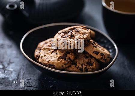 Chocolate cookies with hazelnut and chocolate crumbs with glass of milk and glasses in scene Stock Photo