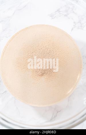 Activating dry yeast in a large glass mixing bowl to prepare the pizza dough. Stock Photo