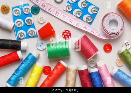 Multicolored spools of thread buttons measuring tape on the table. Close-up top view flat lay Stock Photo