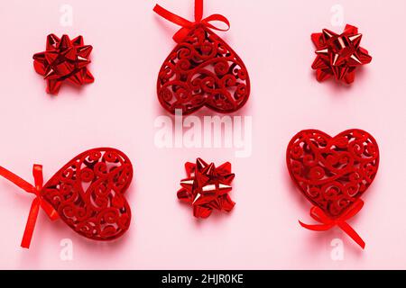 Red Valentine hearts and bows on a pink background. Stock Photo