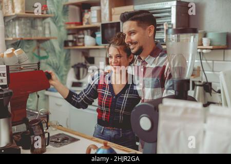 Young lady and man barista standing near the coffee machine Stock Photo
