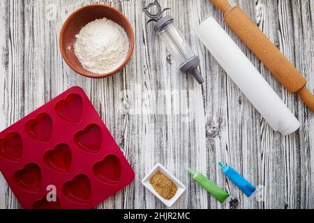 Preparing for baking: heart-shaped silicone mold, rolling pin, confectionery syringe, glaze, flour, sugar. Valentine's day concept. High quality photo Stock Photo