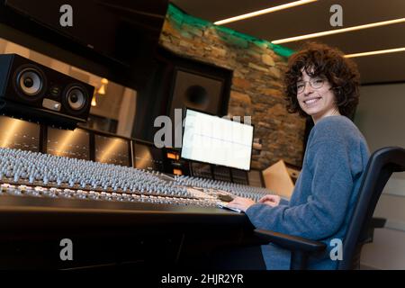 Young woman working in a music studio and smiling at the camera Stock Photo
