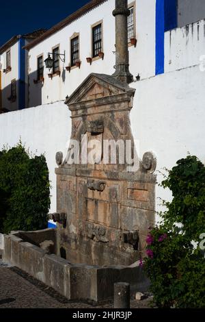 Drinking water fountain and public monument, commissioned in 1575 by Queen Catherine of Austria, in the central square of Óbidos, Portugal Stock Photo