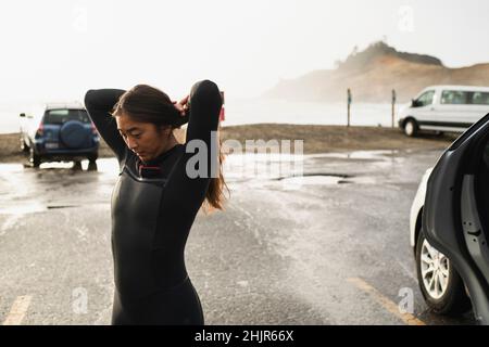 Young woman preparing to surf in coastal Oregon Stock Photo