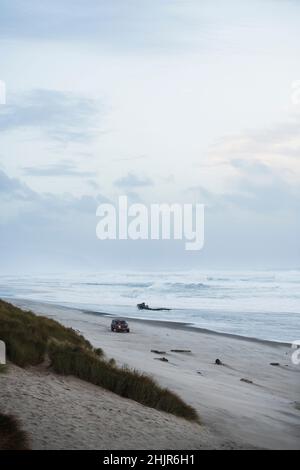 Car on the beach at dusk in coastal Oregon Stock Photo