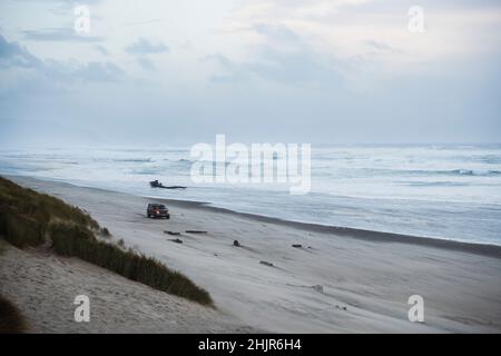 Car on the beach at dusk in coastal Oregon Stock Photo