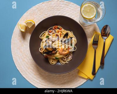Dish of spaghetti allo scoglio top view. Spaghetti with seafood on blu background. Italian food, pasta with shrimps and mussels, clams. Mediterranean Stock Photo