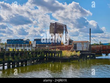 A freight train going over an old bascule railroad bridge,also referred to as a drawbridge or a lifting bridge, with a counterweight. Stock Photo