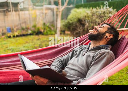 relaxed hipster man in hammock reading a book Stock Photo
