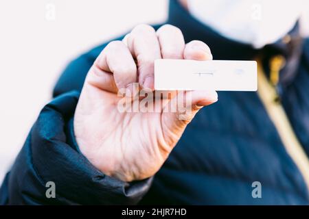 Detail of the hand of an elderly woman in the street holding a negative antigen test. Concept covid-19, ihu, delta, omicron, detection test and pandem Stock Photo