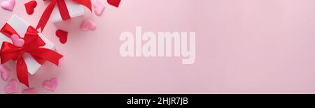 White gift boxes with red ribbon and small red decorative hearts on pink background. Top view with copy space. Valentines day or Wedding romantic conc Stock Photo