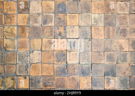Orange brown white beige old shabby worn out floor tiles with damages cracks dirt caverns potholes and paint stains. Art retro grunge design Stock Photo