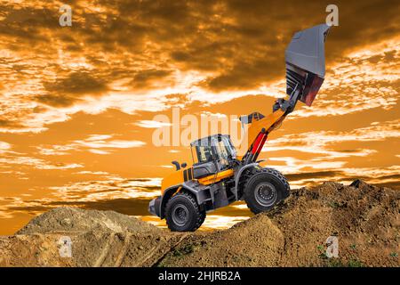 excavator working on construction site in front of dramatic sky Stock Photo