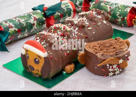 A Christmas themed dog shaped chocolate yule log with Christmas crackers Stock Photo