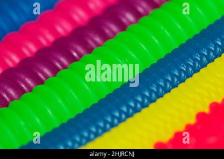 Colorful vibrant rubber cylinder shapes with different abstract patterns and textures on a diagonal slant with selective focus in the center. Stock Photo