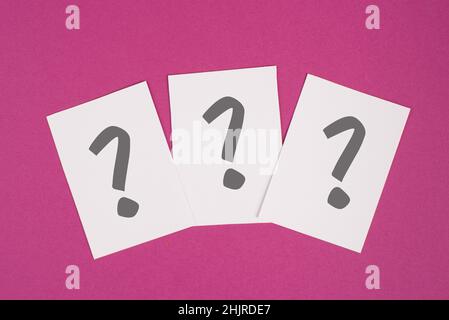 Three colored question marks on paper, vibrant background, looking for an answer, searching for knowledge, problem solving concept Stock Photo