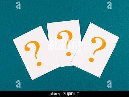 Three colored question marks on paper, vibrant background, looking for an answer, searching for knowledge, problem solving concept Stock Photo