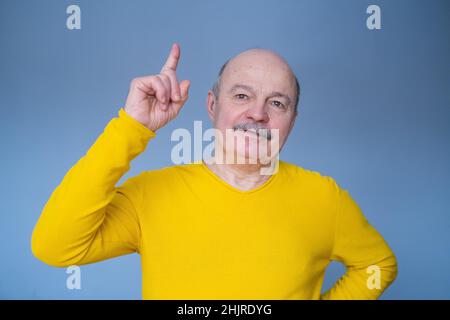 Wow, Eureka. Mature man having great idea, finding inspiration or solution to problem. Excited amazed guy pointing finger up on blue studio background Stock Photo