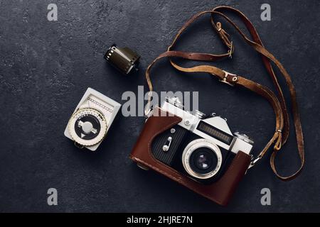 Old retro camera and vintage exposure meter on black background, flat lay Stock Photo