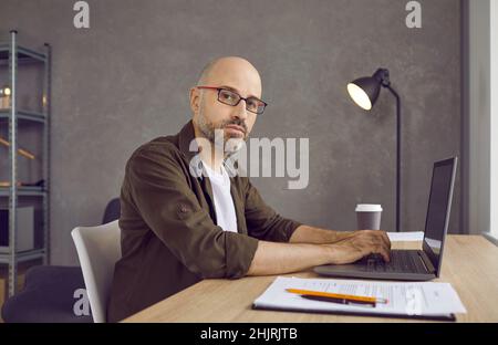 Serious confident businessman typing on laptop, working on project, researching or writing email. Stock Photo