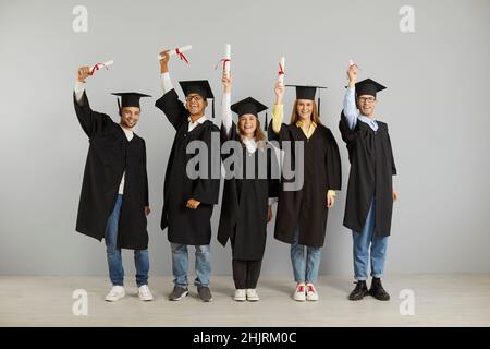 Group of happy successful multiracial graduates who hold their diplomas high in their hands. Stock Photo