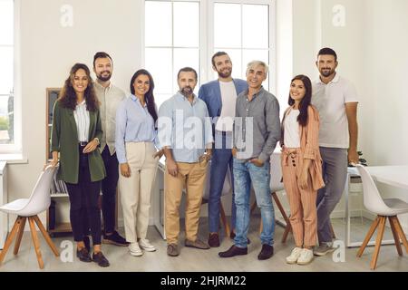 Team of happy confident young and mature business people standing in office and smiling Stock Photo