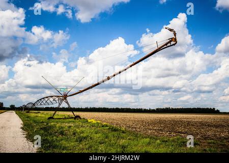 A beautiful sunny day in the country. Looking down the long drive way with a huge sprayer sitting nearby with the field and sky in the background. Stock Photo