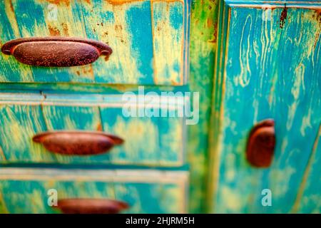 Old dresser drawers rusty handles with faded peeling green and blue paint Stock Photo