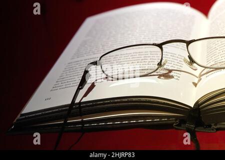 Close up of reading glasses lying on open book, selective focus Stock Photo