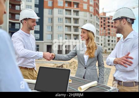 Friendly young builder shaking hands with a pleased woman supervisor Stock Photo